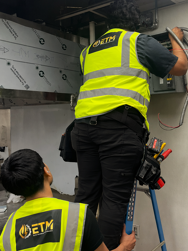 Two ETM technicians servicing an electrical panel